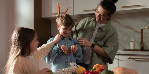 Mother and children have fun unpacking vegetables in the kitchen.
